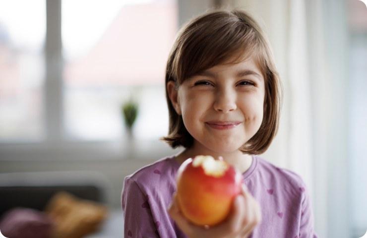 Smiling girl holding up a half-eaten apple