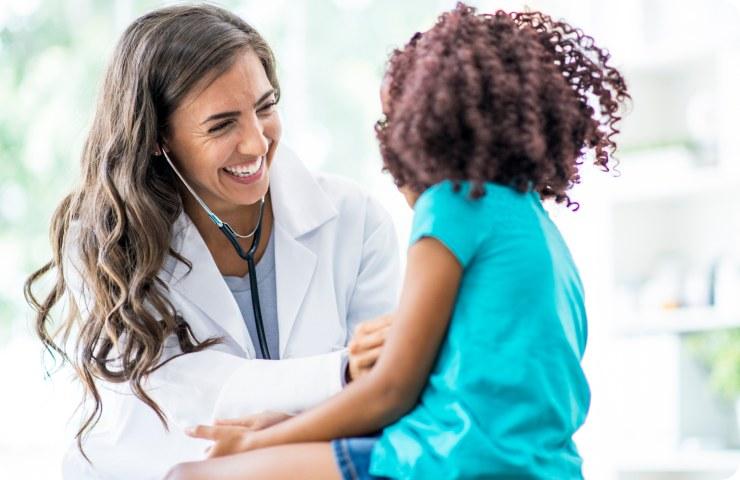 Pediatrician sharing a laugh with a young patient during a checkup