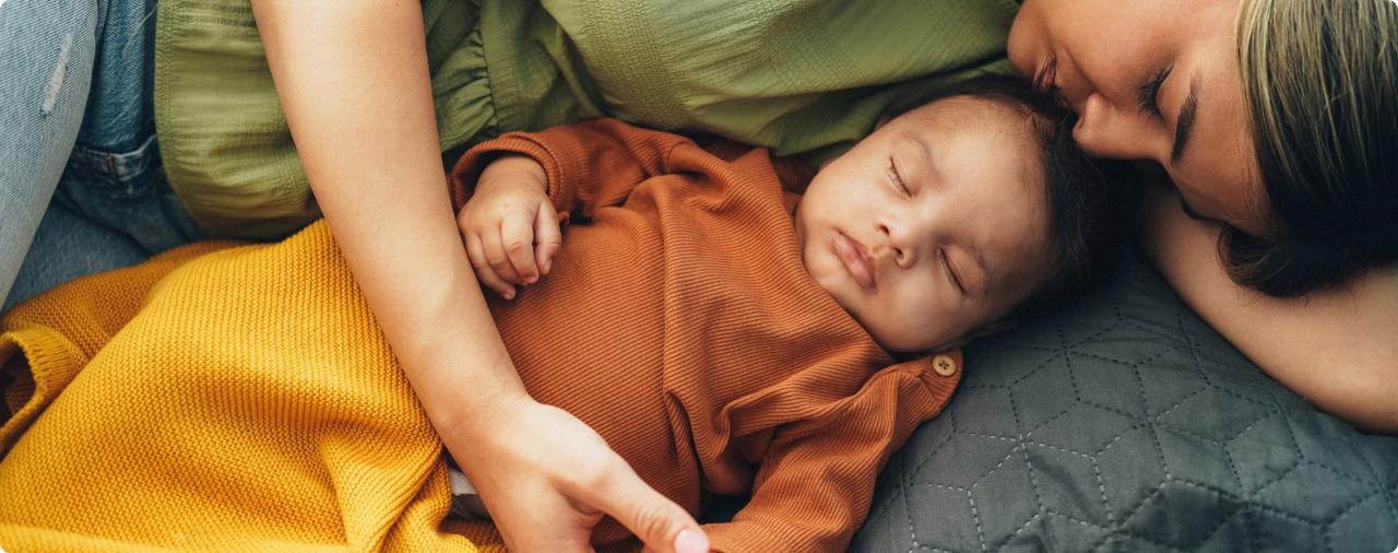 Mother resting beside her sleeping baby