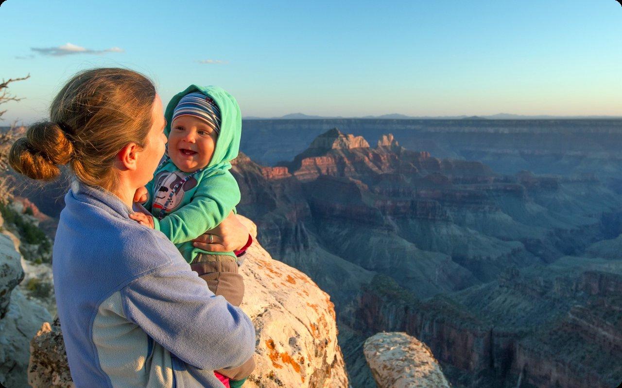 Mother holding her smiling baby at the rim of the Grand Canyon