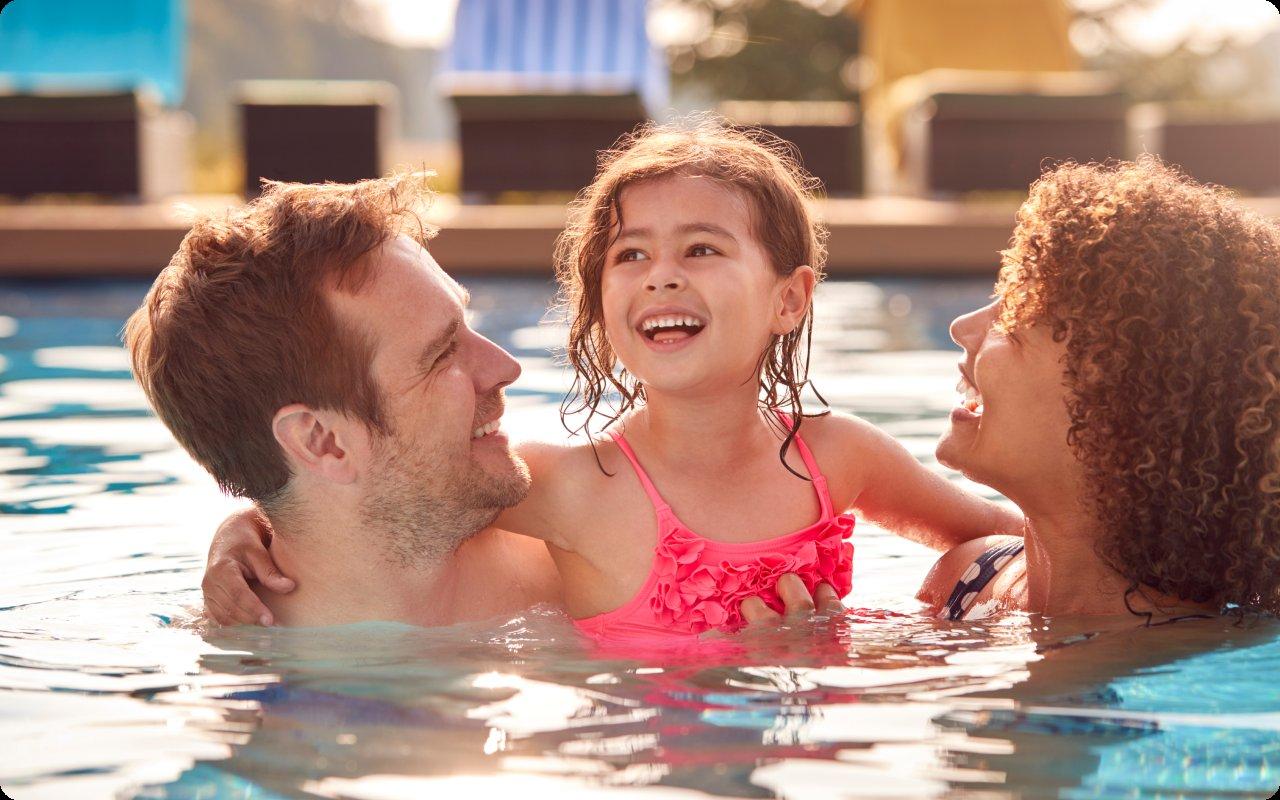 Parents and their daughter laughing together in a swimming pool