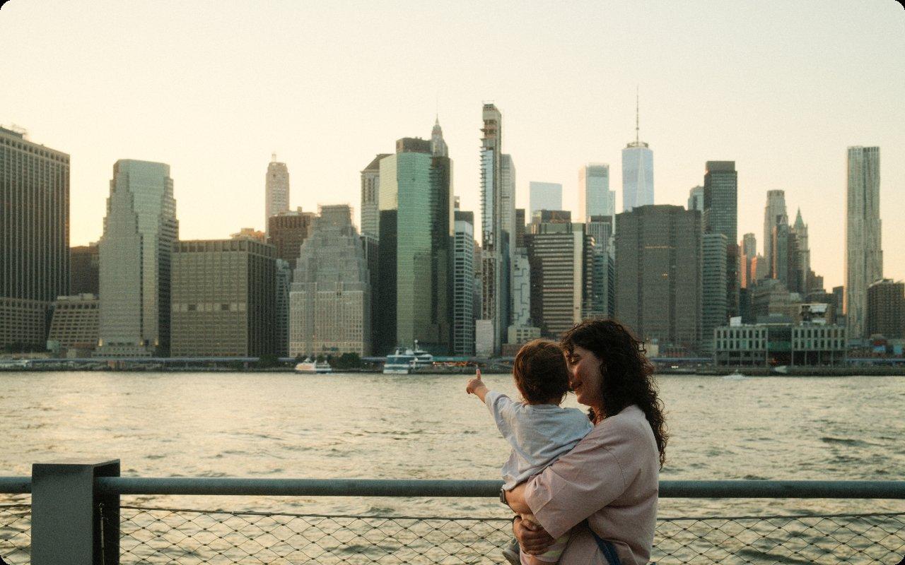 Mother holding her child as they point out at the Manhattan skyline