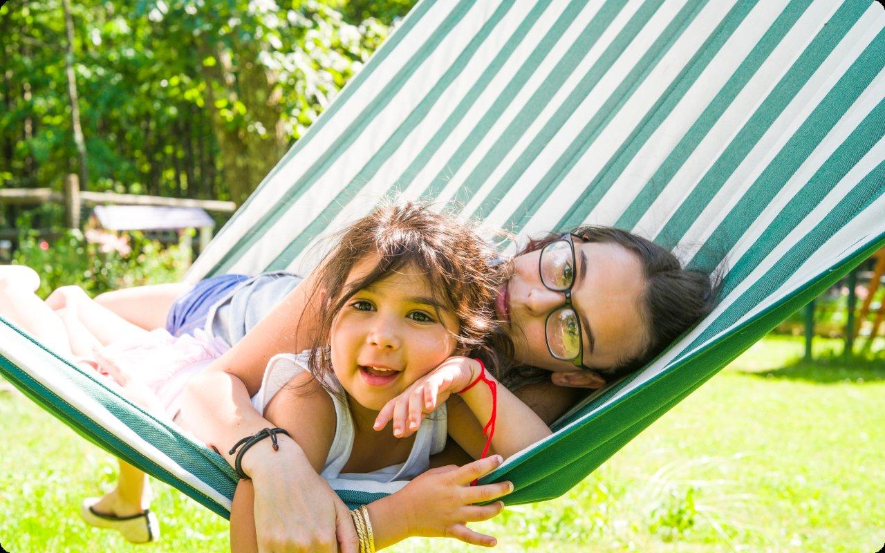 Two girls relaxing together in a striped backyard hammock