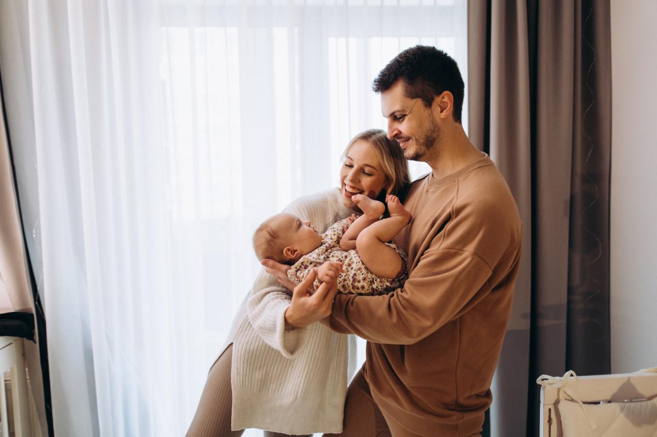 Parents cradling their baby beside a bright window