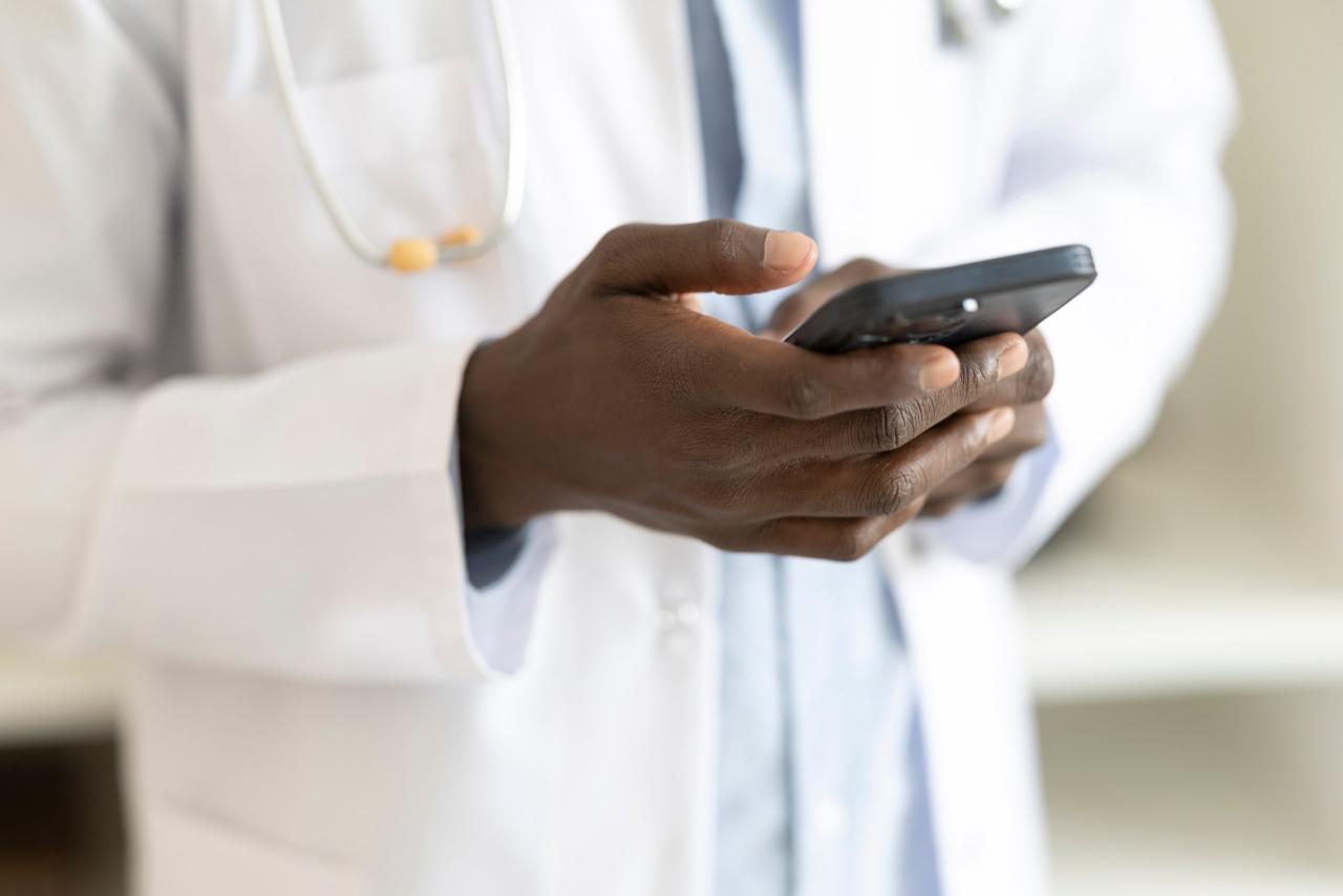 Close-up of a doctor's hands typing on a smartphone